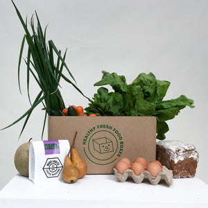 The Healthy Box includes 6 vegetables, 2 fruits, freshly baked bread, half a dozen eggs, and a Grocery Surprise. The box pictured is packed with spring onions, carrots, zucchinis, pears, and a melon. The Grocery Surprise shown is a bag of premium coffee beans from Wood and Co Coffee Roasters. All produced included were sourced organically and from local Australian businesses.